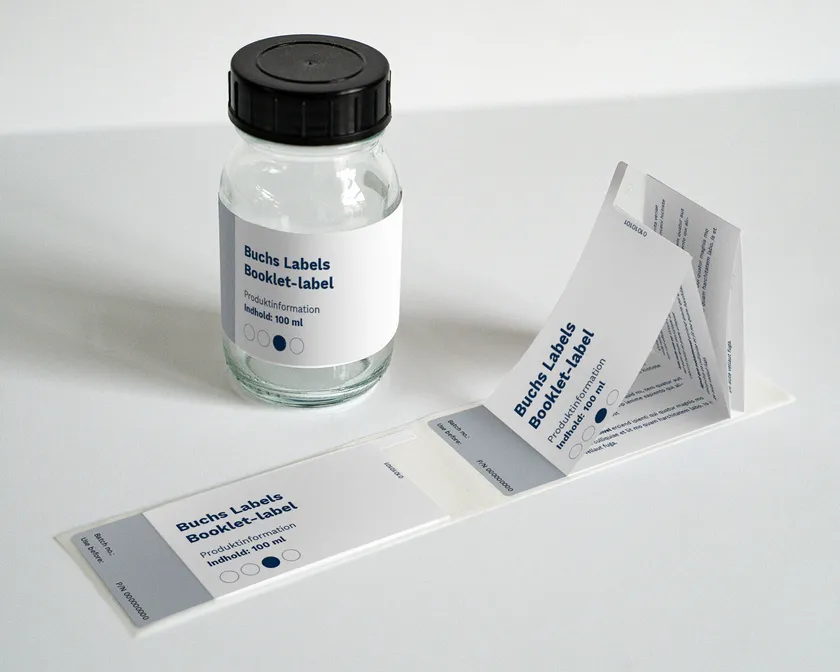 Booklet-label ved siden af en medicinflaske fra Buchs Labels